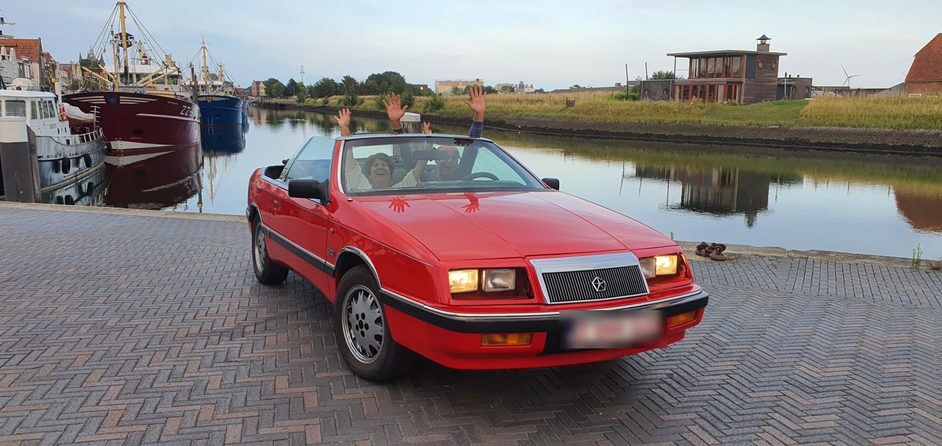 Rode Chrysler Le Baron cabrio aan de haven in de zon