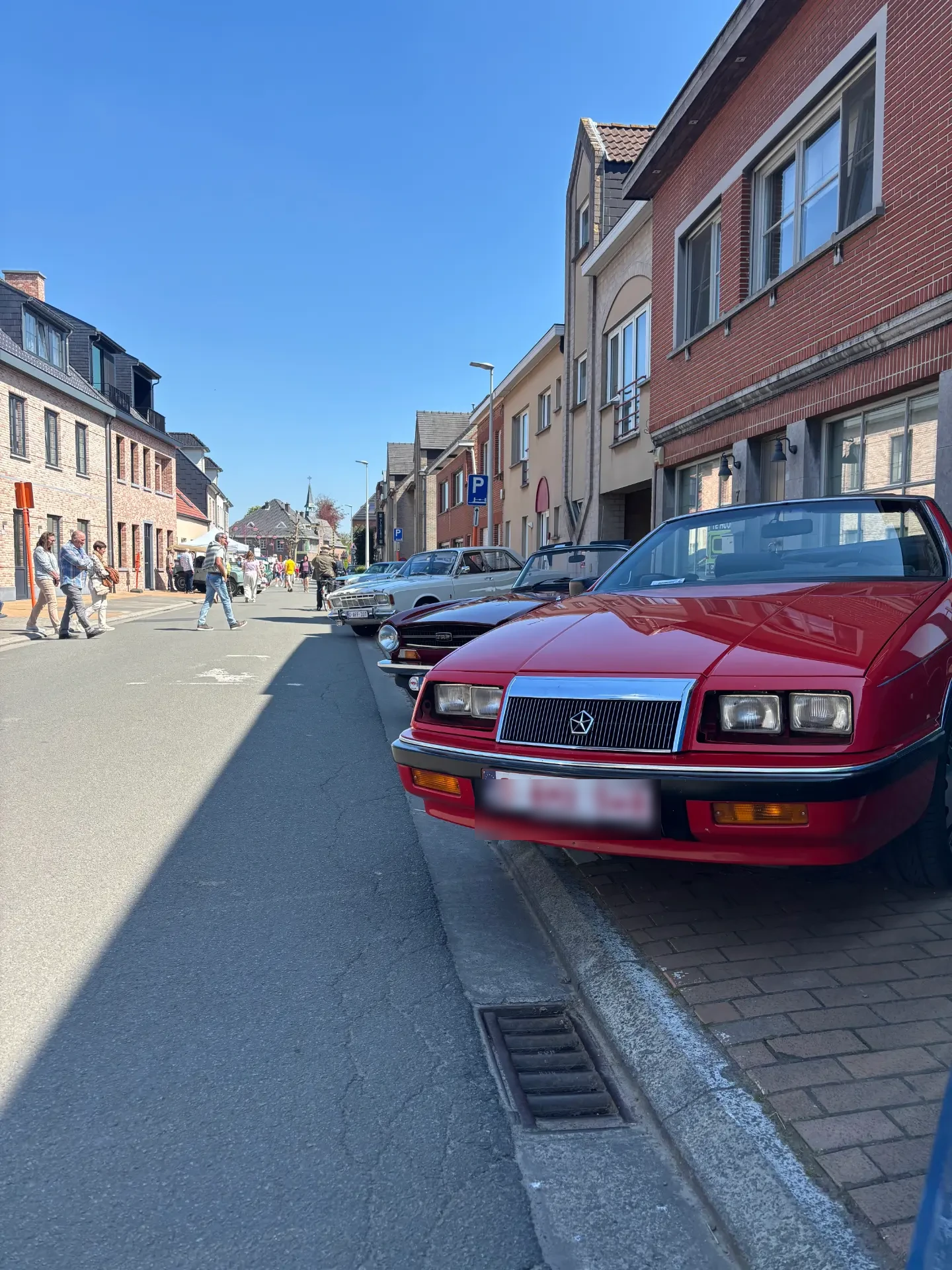De rode cabrio tussen andere oldtimers tijdens een meeting